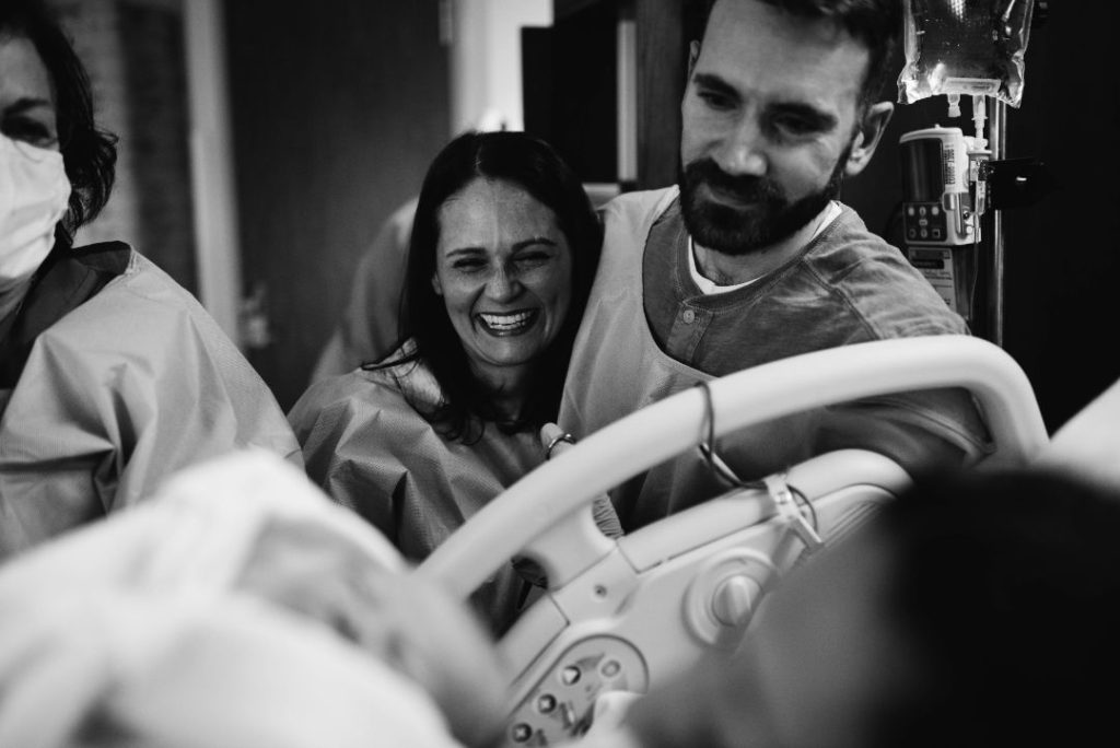 couple looking at a hospital bed and a new baby smiling